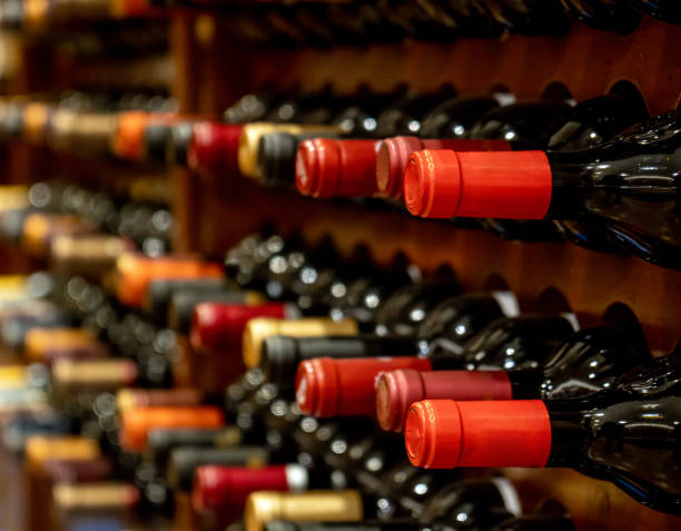 Bottles of black red wine lined up and stacked on wooden wine rack shelves from a private collection of a wine cellar in Spain.